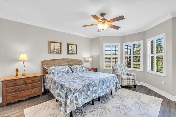 Bedroom with ornamental molding, hardwood / wood-style flooring, and ceiling fan