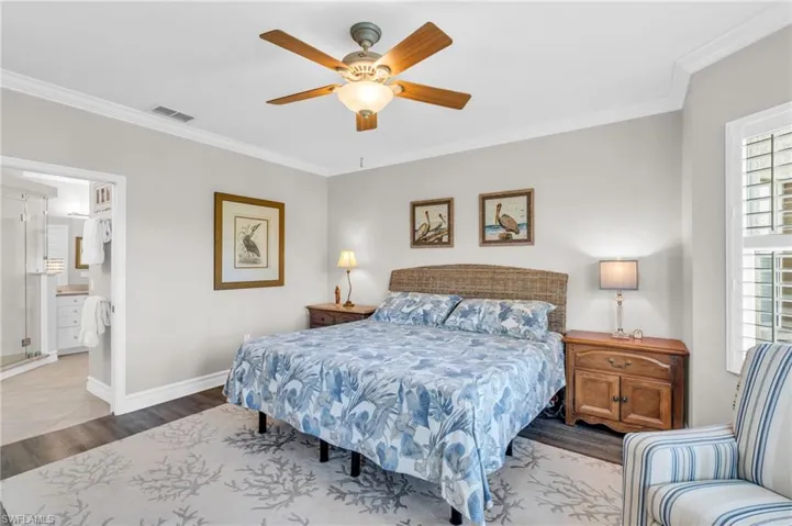 Bedroom with ceiling fan, crown molding, ensuite bath, and hardwood / wood-style floors