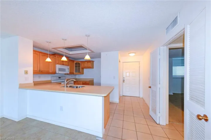 Kitchen featuring sink, range, decorative light fixtures, light tile patterned floors, and kitchen peninsula