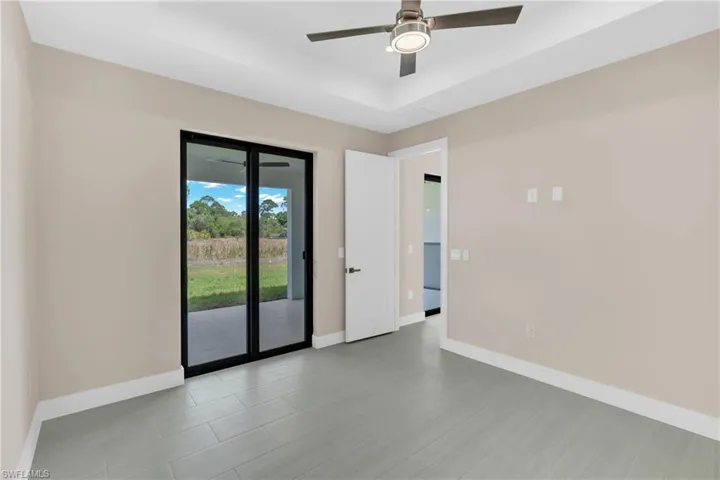 Spare room featuring a ceiling fan, a raised ceiling, and light wood-style floors
