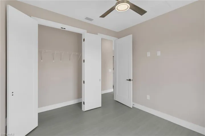 Unfurnished bedroom with a closet, a ceiling fan, and dark wood-style floors