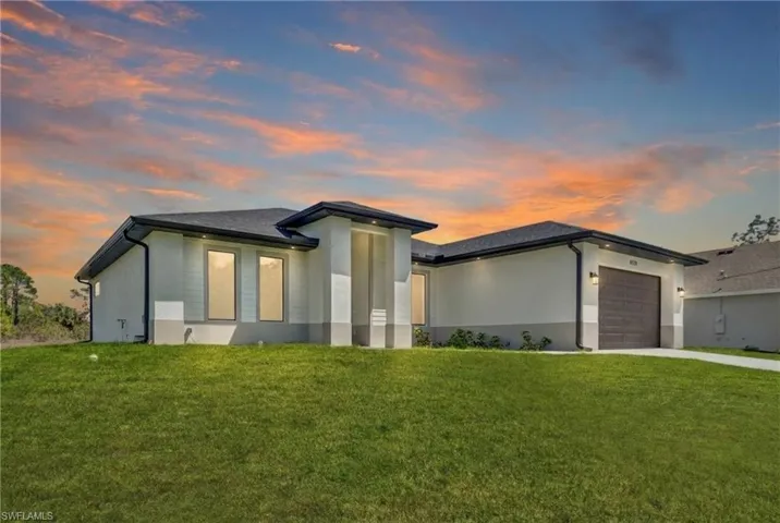 View of front of property with a yard, a garage, stucco siding, and concrete driveway