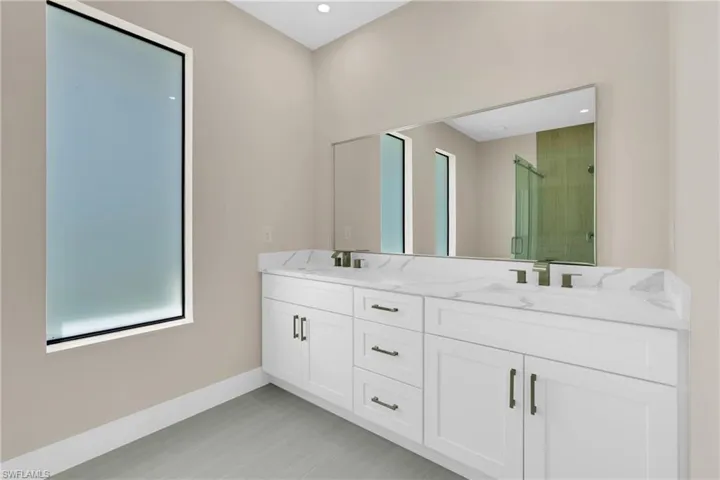 Bathroom with double vanity, a stall shower, and recessed lighting