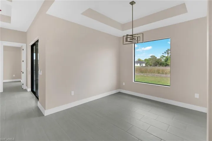 Empty room featuring a tray ceiling and a chandelier