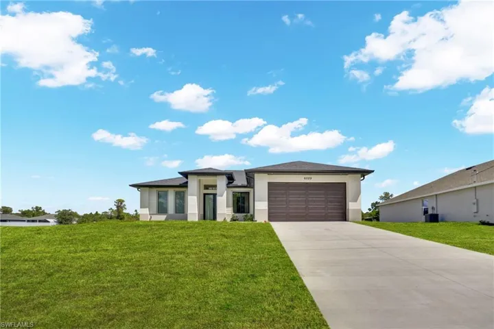 Prairie-style house with a front lawn, an attached garage, stucco siding, and concrete driveway