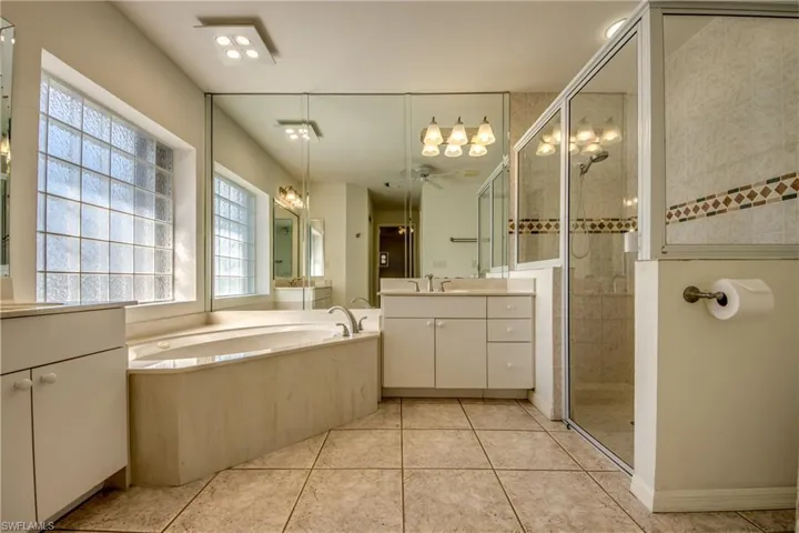 Bathroom featuring tile patterned flooring, plus walk in shower, vanity, and ceiling fan
