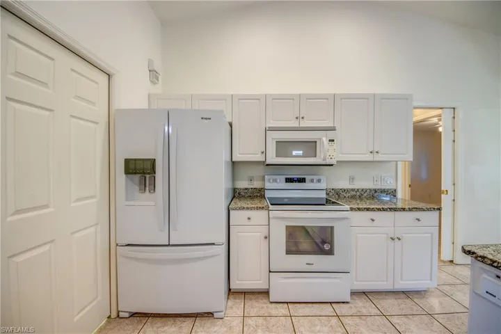 Kitchen with white cabinetry, white appliances, and light tile patterned floors
