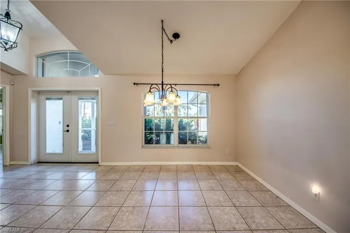 Entryway featuring high vaulted ceiling, light tile patterned floors, a chandelier, and french doors