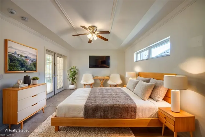 Tiled bedroom featuring multiple windows, a tray ceiling, access to outside, and french doors