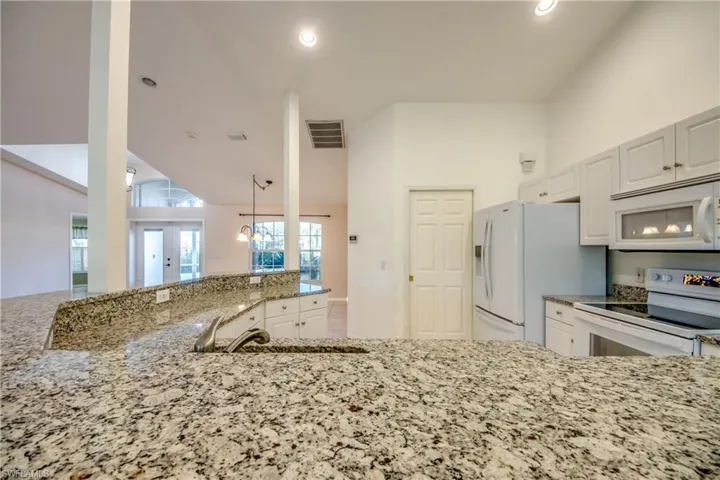 Kitchen featuring french doors, sink, white appliances, light stone countertops, and white cabinets