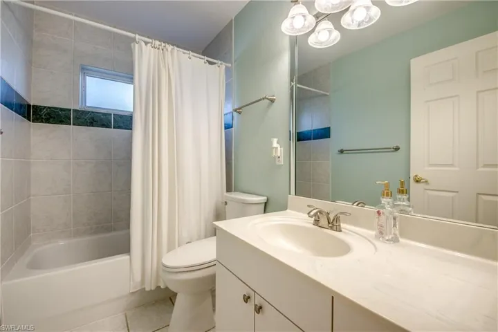 Full bathroom featuring shower / bathtub combination with curtain, tile patterned floors, toilet, and vanity