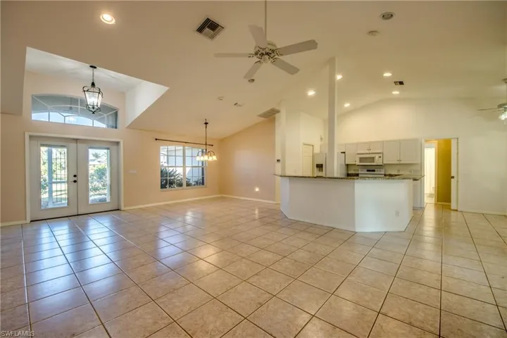 Kitchen featuring pendant lighting, white cabinetry, light tile patterned floors, kitchen peninsula, and white appliances