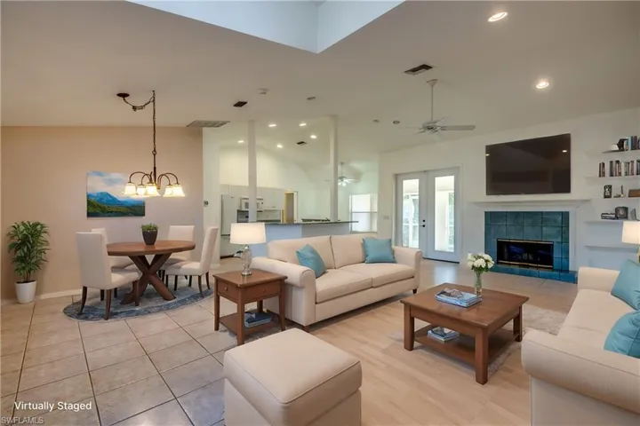 Living room featuring a tiled fireplace, ceiling fan with notable chandelier, and high vaulted ceiling