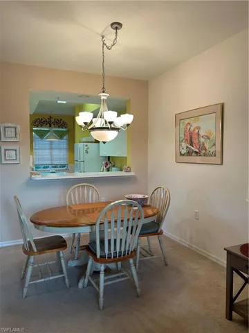 Carpeted dining space with a chandelier and baseboards