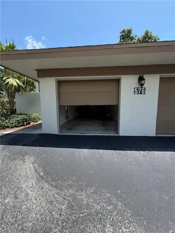 Attached garage with a tan overhead door, stucco exterior, and black house numbers