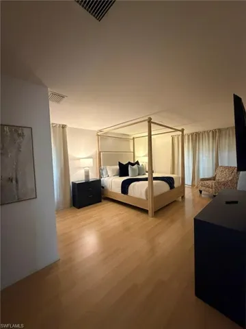 Spacious room featuring wood-finish flooring, white walls, and recessed lighting