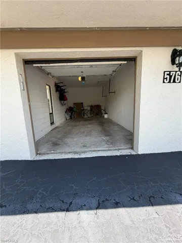 Single-car garage with a concrete floor, automatic door opener, and interior lighting