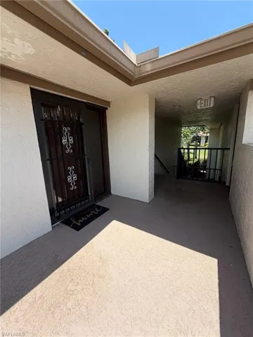 Entryway with textured stucco walls, a dark wood door, and an ornate wrought iron security gate