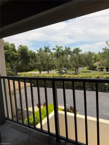 Outdoor balcony with black metal railing, offering expansive views of mature trees and tropical landscaping