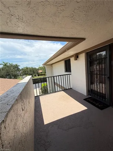 Private outdoor balcony featuring a textured wall, black metal railing, and a secure entry door with decorative ironwork