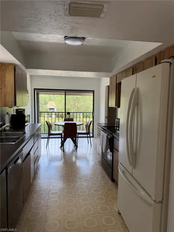 Galley kitchen featuring wood cabinetry, dark countertops, and patterned flooring