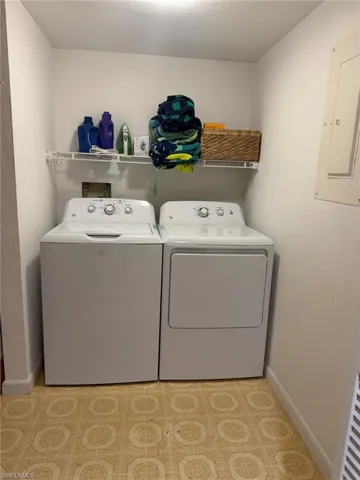 Dedicated laundry area featuring a washer and dryer, patterned floor tile, and overhead wire shelving for storage
