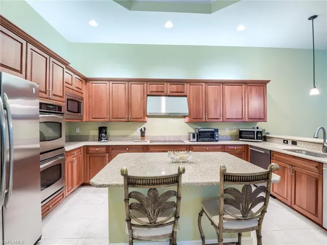 Kitchen featuring stainless steel appliances, a kitchen bar, hanging light fixtures, and sink
