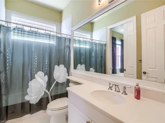Bathroom with a shower with shower curtain, tile patterned floors, vanity, and toilet