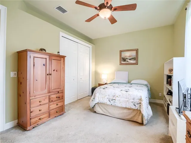 Carpeted bedroom with ceiling fan and a closet