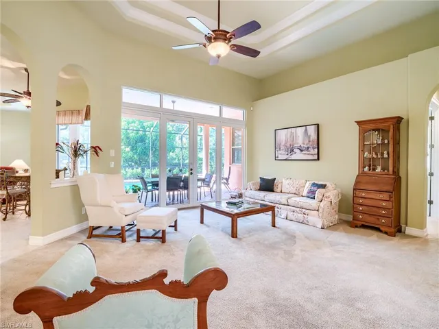Carpeted living room featuring ceiling fan, a high ceiling, french doors, and a healthy amount of sunlight