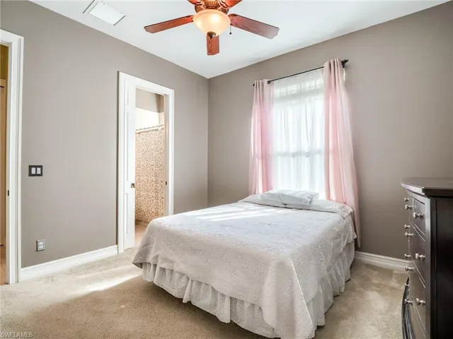 Bedroom featuring light carpet, ensuite bathroom, and ceiling fan