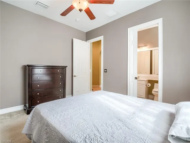 Bedroom with ceiling fan, light carpet, and ensuite bathroom