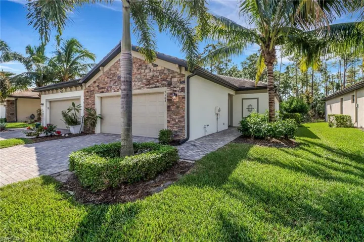 View of front of home featuring stone siding, stucco siding, a front lawn, decorative driveway, and a garage