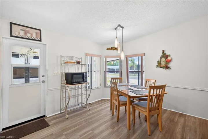 The dining area features hard flooring, a decorative pendant light fixture, and windows providing natural light