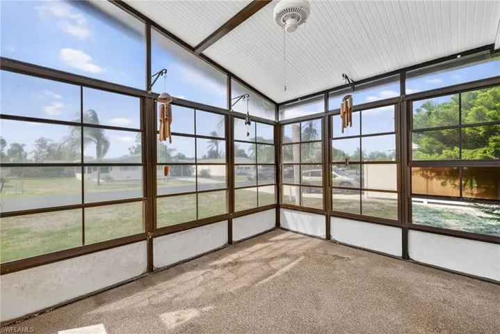 This screened enclosure features a textured floor, a white paneled ceiling, and a ceiling fan