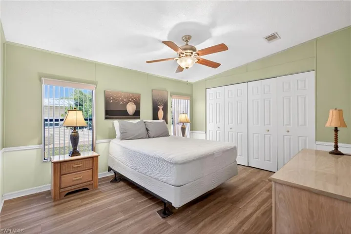 This room features wood-look flooring, a ceiling fan with lighting, and white bi-fold closet doors