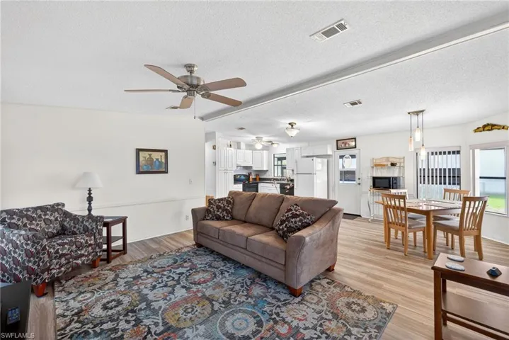 Open concept living space featuring a ceiling fan, light-colored flooring, and white walls