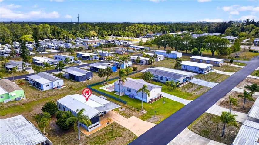 Aerial view of the property and its surrounding area, featuring paved roads, green lawns, and scattered palm trees