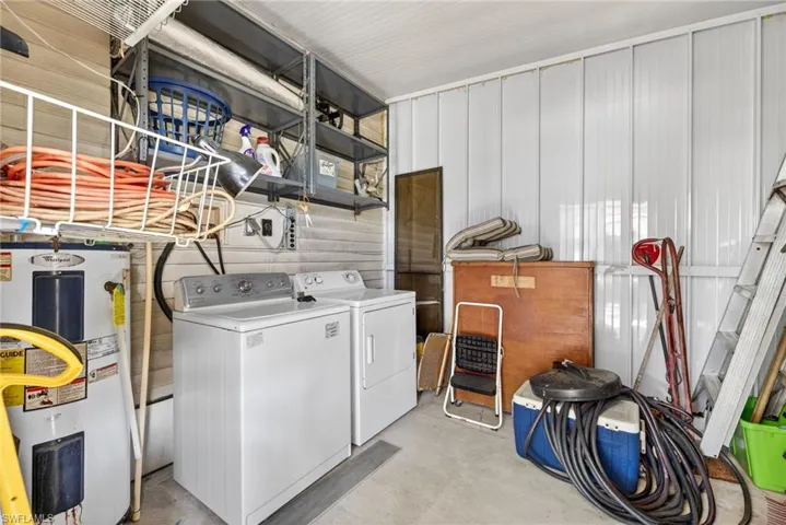 This utility space features a washer and dryer, a water heater, and overhead shelving for storage