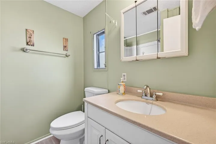 Bathroom featuring a vanity with a countertop sink, a wall-mounted mirror cabinet, and a window providing natural light