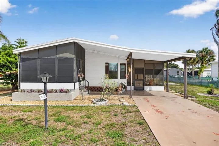 The property features a screened-in porch, a carport, and a well-maintained lawn with landscaping