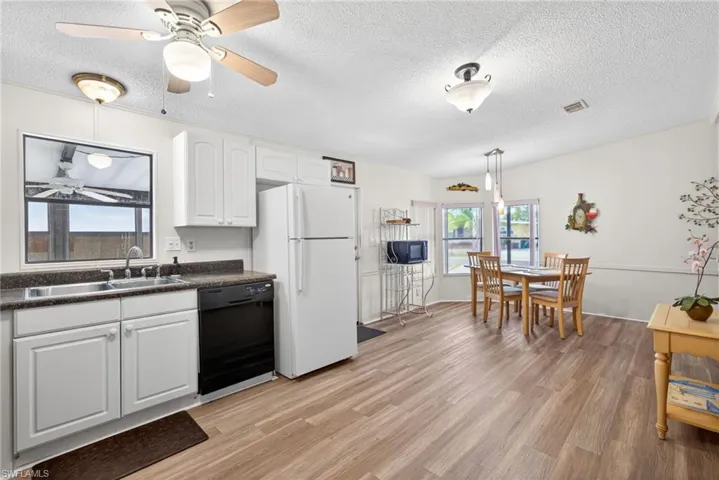 This property features an open-concept living area with wood-look flooring, a kitchen with white cabinetry, and a dining area with pendant lighting