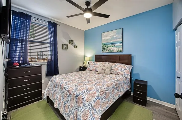 Bedroom with ceiling fan, dark hardwood / wood-style floors, and a closet
