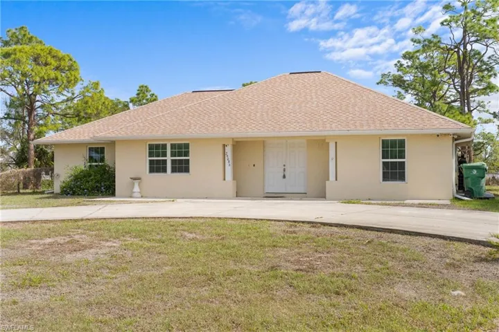 Ranch-style home with stucco siding, a shingled roof, and a front yard