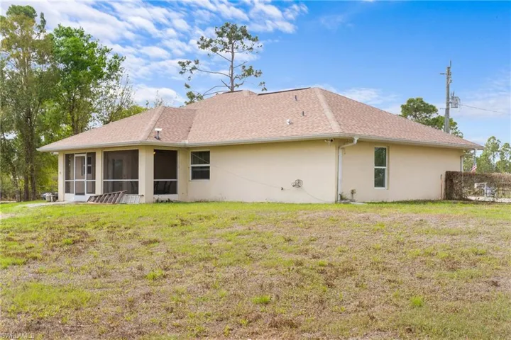 Back of house featuring a lawn, stucco siding, and a sunroom