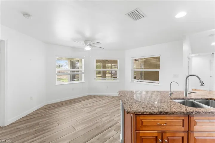 Kitchen featuring light wood finished floors, dark stone countertops, wood finish cabinets, ceiling fan, and open floor plan