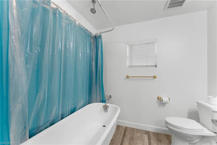 Full bath featuring light wood-style flooring and a combined bath / shower with freestanding tub