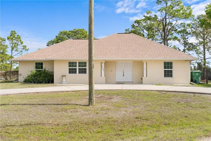 Ranch-style home with stucco siding, a front lawn, and roof with shingles