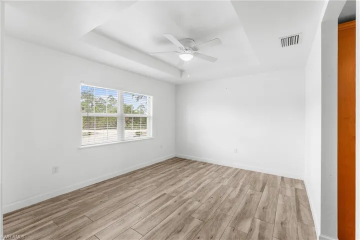 Empty room featuring wood tiled floors, ceiling fan, and a raised ceiling