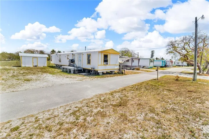 Manufactured / mobile home featuring driveway and an outdoor structure